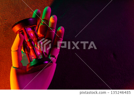 Futuristic Robotic Hand Holding Vintage Hourglass with Neon Orange Green Purple Lighting 135246485