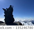 山頂上矗立著一座守護神像，俯瞰著雲海和藍天。 135246780