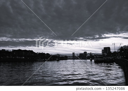 Evening view of the Main River and the Eiserner Steg railway bridge in Frankfurt, Germany. Monochrome cityscape. 135247086