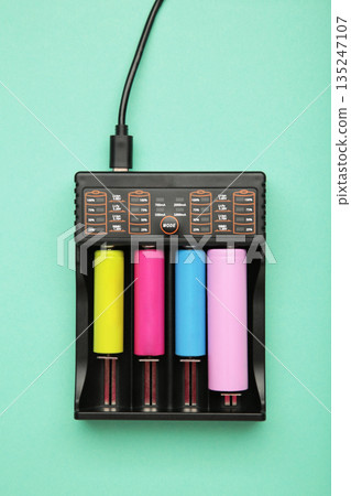 Rechargeable batteries in a battery charger. Four batteries in a charger. NI-MH and LI-MH battery. Vertical photo Rechargeable batteries in a battery charger. Four batteries in a charger. NI-MH and LI-MH battery. Vertical photo 135247107