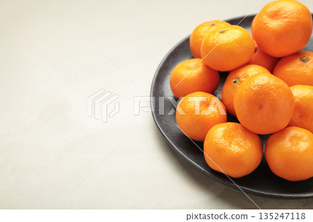 Fresh small tangerine mandarin orange in a plate on light background. 135247118