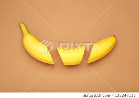 Cut banana, slices on light brown background. Minimalist concept. Cut banana, slices on light brown background. Minimalist concept. 135247133