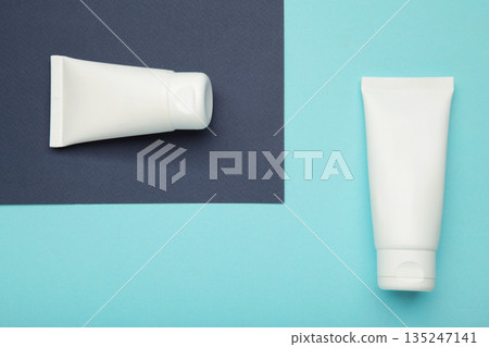 White plastic cosmetic tubes on blue background. Space for text White plastic cosmetic tubes on blue background. Space for text 135247141