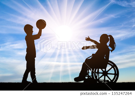 Boy holding a ball and a girl in a wheelchair reaching out to catch it 135247264