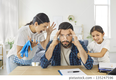 Stress and despair of father over chaos and noise at home, man sitting at table Stress and despair of father over chaos and noise at home, man sitting at table 135247596