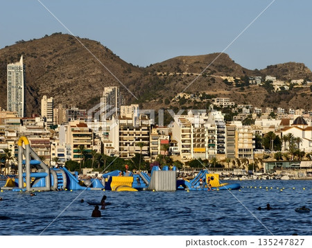 vibrant seaside water fun, lively summer scene with inflatable structures and swimming fun at sunset 135247827