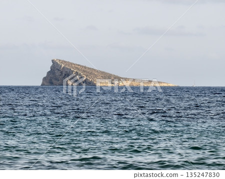 solitary rocky islet with textured sea waves, lone rocky islet emerges from turquoise waters at dawn 135247830