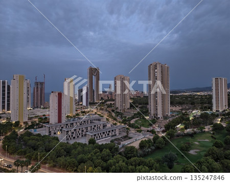 urban twilight with lit windows, serene evening view of city buildings and natural surroundings urban twilight with lit windows, serene evening view of city buildings and natural surroundings 135247846