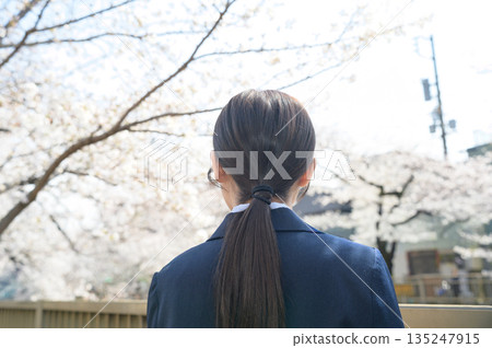 一位女子背對著鏡頭，抬頭望著櫻花。 135247915