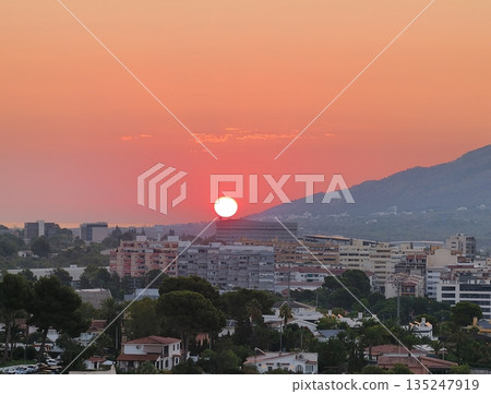 Peaceful horizon with sunset illuminating city and seaside Peaceful horizon with sunset illuminating city and seaside 135247919