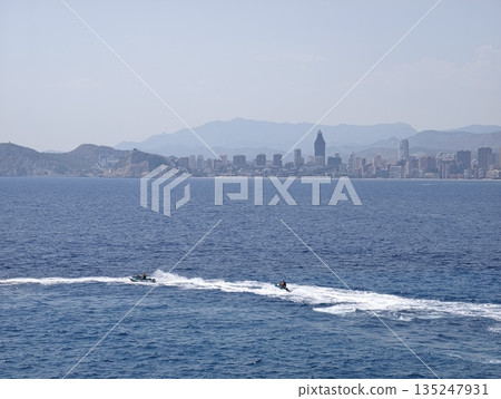 Vibrant summer scene featuring jet skis racing over blue water Vibrant summer scene featuring jet skis racing over blue water 135247931