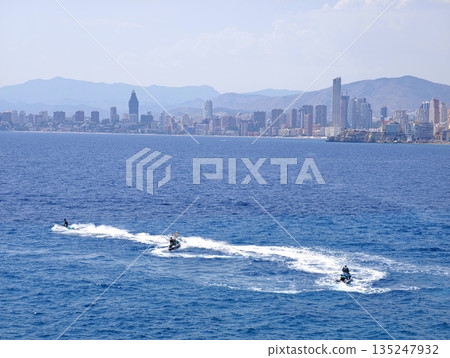 Thrilling jet ski ride near urban skyline and mountain views 135247932