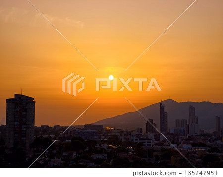 Calm sunset scene featuring distant mountains and urban skyline 135247951