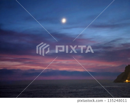 Twilight shoreline with glowing cliffs and shimmering waters 135248011