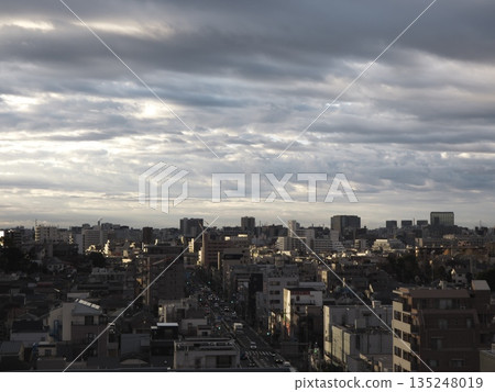 A panoramic view of the city with light pouring through the clouds. Tokyo's cityscape and densely packed buildings spread out under a dramatic sky. A panoramic view of the city with light pouring through the clouds. Tokyo's cityscape and densely packed buildings spread out under a dramatic sky. 135248019
