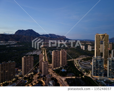 mountain skyline with glowing lights, dusk city horizon featuring towering structures and winding streets mountain skyline with glowing lights, dusk city horizon featuring towering structures and winding streets 135248037