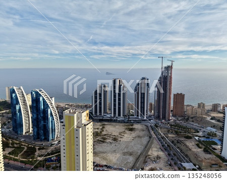 building development near ocean shore, urban project with heavy equipment overlooking ocean horizon 135248056
