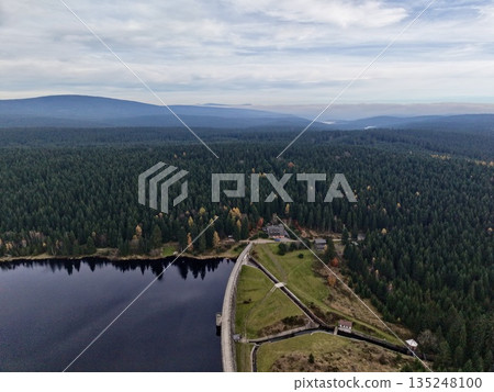aerial perspective of tranquil water and dense forest with small dwellings and winding roads aerial perspective of tranquil water and dense forest with small dwellings and winding roads 135248100