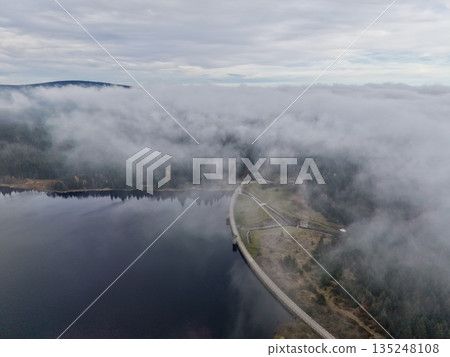 misty waters with distant woods, serene morning with low clouds and muted colors surrounding calm dam misty waters with distant woods, serene morning with low clouds and muted colors surrounding calm dam 135248108