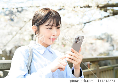 A woman using a smartphone under a cherry tree 135248273