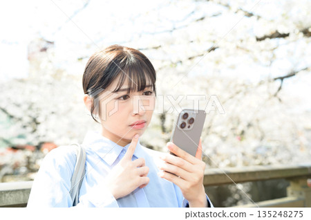 A woman using a smartphone under a cherry tree 135248275