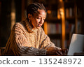 Woman works on laptop in warm sweater light home office 135248972