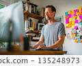 Man Working from Home at Standing Desk Using Computer,  Organized Workspace with Books and Notes 135248973