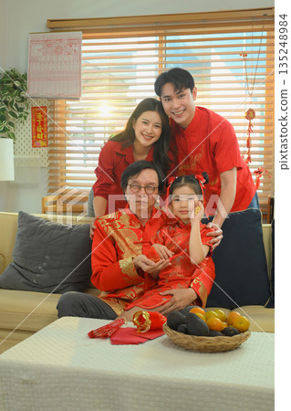 Happy multigenerational family poses together in red outfits during a Chinese New Year celebration 135248984