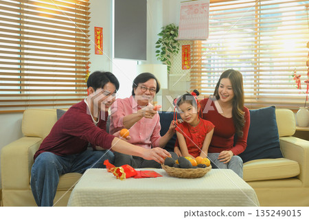 Asian family relaxing together on sofa, watching television after a Chinese New Year meal Asian family relaxing together on sofa, watching television after a Chinese New Year meal 135249015