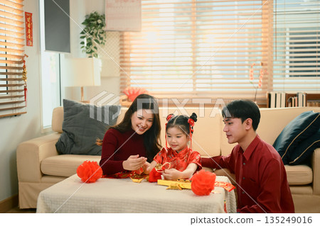 Asian family sit together decorating red lanterns ornaments for Chinese New Year, sharing a joyful family moment Asian family sit together decorating red lanterns ornaments for Chinese New Year, sharing a joyful family moment 135249016