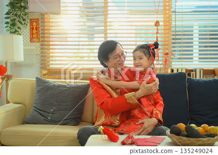 Grandfather hugs his granddaughter with love while celebrating Chinese New Year together in a warm and peaceful family home 135249024