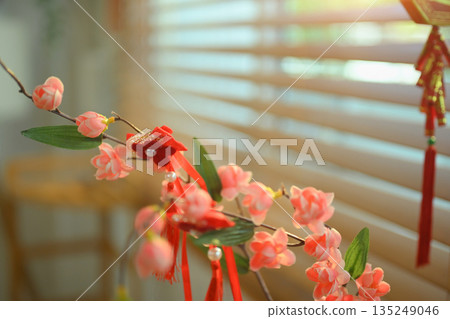 Sakura flowers with red tassel ornaments in warm sunlight, creating a calm Chinese New Year decoration Sakura flowers with red tassel ornaments in warm sunlight, creating a calm Chinese New Year decoration 135249046