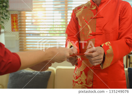 Hands exchange a red envelope as a traditional gift during Chinese New Year, symbolizing blessings, prosperity, and good fortune Hands exchange a red envelope as a traditional gift during Chinese New Year, symbolizing blessings, prosperity, and good fortune 135249076