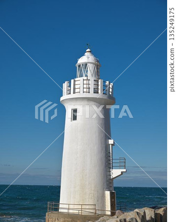 Irago Cape Lighthouse towers into the blue sky. A white lighthouse watching over the Pacific Ocean. Irago Cape Lighthouse towers into the blue sky. A white lighthouse watching over the Pacific Ocean. 135249175