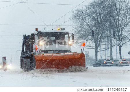 Snowplow truck removing dirty snow from city street or highway during heavy snowfalls. Traffic road situation. Bad weather conditions forecast for drivers. Seasonal road maintenance Europe Germany Snowplow truck removing dirty snow from city street or highway during heavy snowfalls. Traffic road situation. Bad weather conditions forecast for drivers. Seasonal road maintenance Europe Germany 135249217