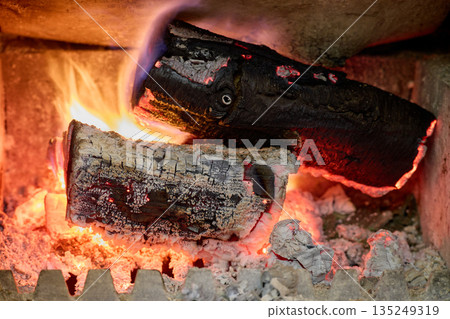 Burning Firewood Logs Glowing in Fireplace Close Up 135249319