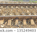 Close-up of railway tracks with gravel stones and wooden sleepers 135249403