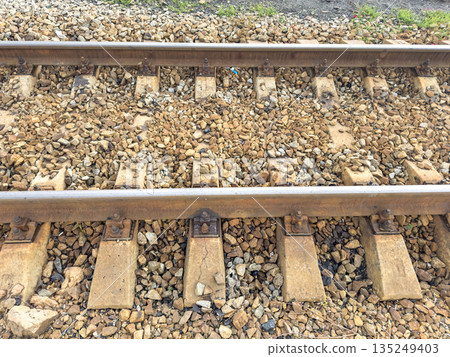 Close-up of railway tracks with gravel stones and wooden sleepers Close-up of railway tracks with gravel stones and wooden sleepers 135249403