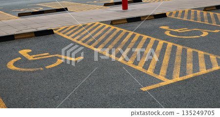 Yellow markings designating accessible parking spots on asphalt surface. The concept represents accessibility, inclusion, and organized infrastructure 135249705