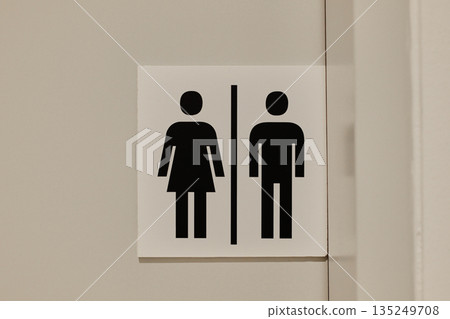 Simple black unisex restroom sign on a neutral wall. The concept represents clarity, universal design, and gender equality 135249708
