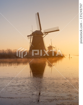 Traditional Dutch landscape with warm sun light, water reflections, and calm morning atmosphere.  135249797