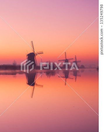 Traditional Dutch landscape with warm sun light, water reflections, and calm morning atmosphere.  135249798