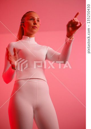 Female in smartglasses gesturing against red background Female in smartglasses gesturing against red background 135250430