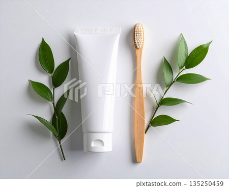 Flat lay. Minimalistic bamboo toothbrush with a tube of natural toothpaste on a white background. Health care. Oral hygiene. 135250459