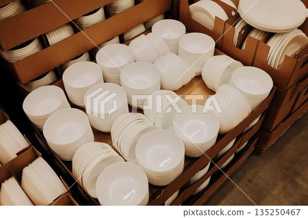 Neat arrangement of white ceramic bowls packed in cardboard boxes. Represents order, minimalism, and modern household design 135250467
