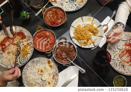 Traditional Indian meals with colorful spices, rice, curry and flatbread served on decorated table. Traditional Indian meals with colorful spices, rice, curry and flatbread served on decorated table. 135250628