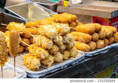 韓國人氣美食,如熱狗和起司熱狗,在各個小吃攤位前整齊排列。 韓國人氣美食,如熱狗和起司熱狗,在各個小吃攤位前整齊排列。 135250894