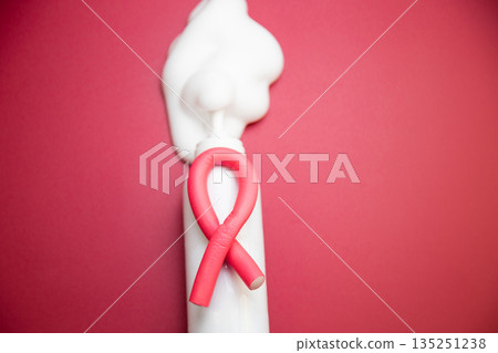 A close-up in the center of a bottle of foam for long-lasting hair styling lies on a pink background, white foam has poured out of it, a curved pink curler lies on it. The concept of styling 135251238