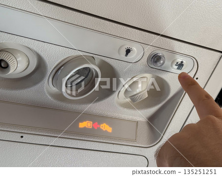 Airplane passenger pressing the flight attendant call button. Communication, service, and assistance during air travel. 135251251