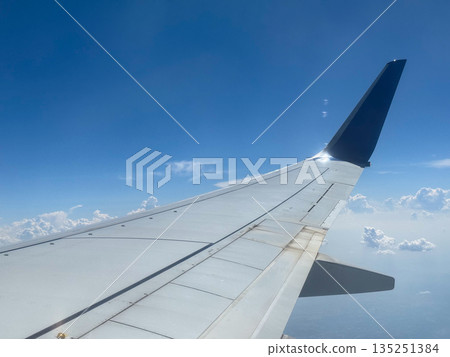 Airplane wing with winglet flying above clouds. Technology, travel, and aviation industry in modern transportation. Airplane wing with winglet flying above clouds. Technology, travel, and aviation industry in modern transportation. 135251384